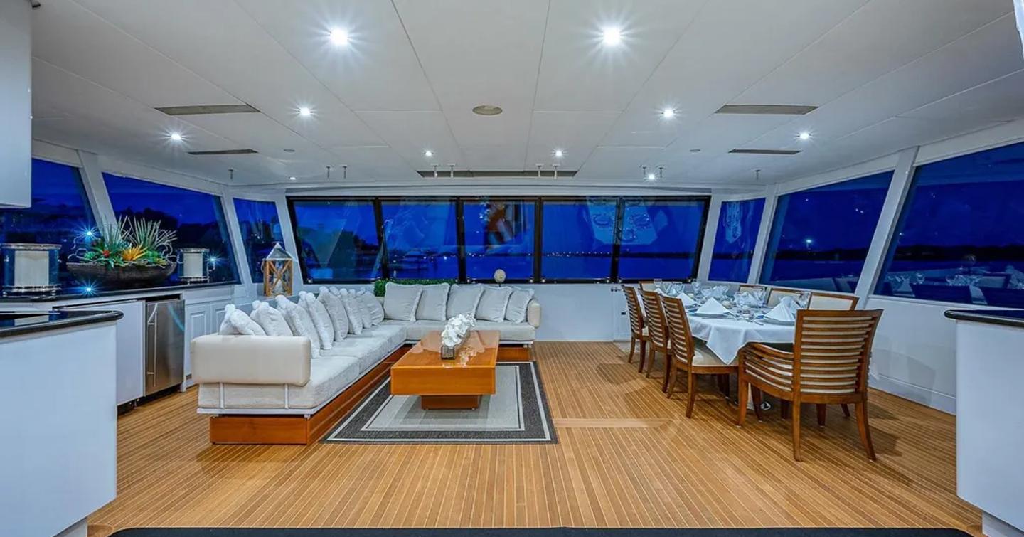 Superyacht La Sirena's enclosed main aft deck with dining table and L-shaped sofa