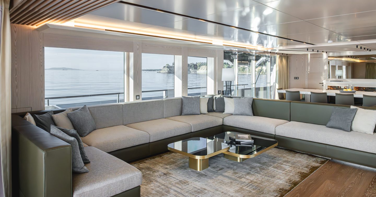 Explorer yacht Mitan main saloon with grey U-shaped sofa and glass coffee tabele 