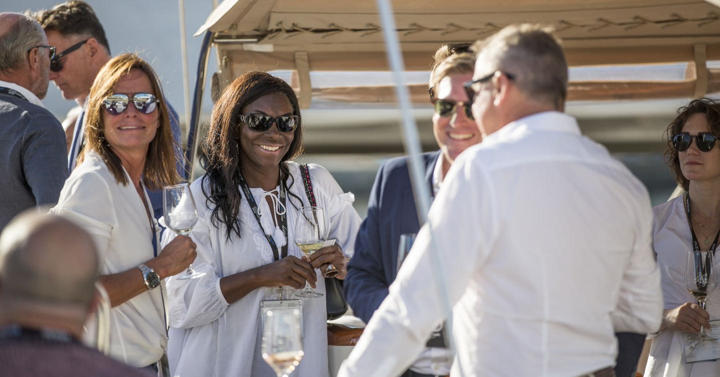 A group of visitors at the Palma International Boat Show in discussion with drinks