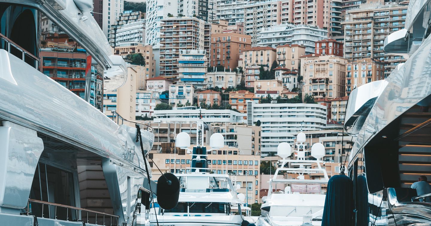 View of Monte Carlo through berthed superyachts in Port Hercule.