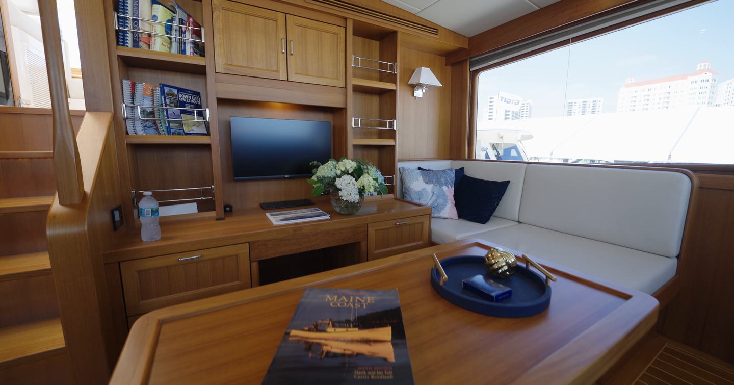 Fleming 85 pilothouse lounge with custom office workspace, built-in storage and large side window