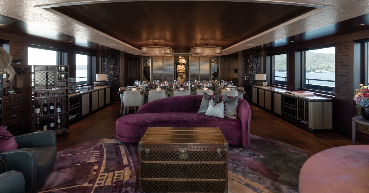 Interior of superyacht Pink Shadow main saloon with purple seating and aft dining area 