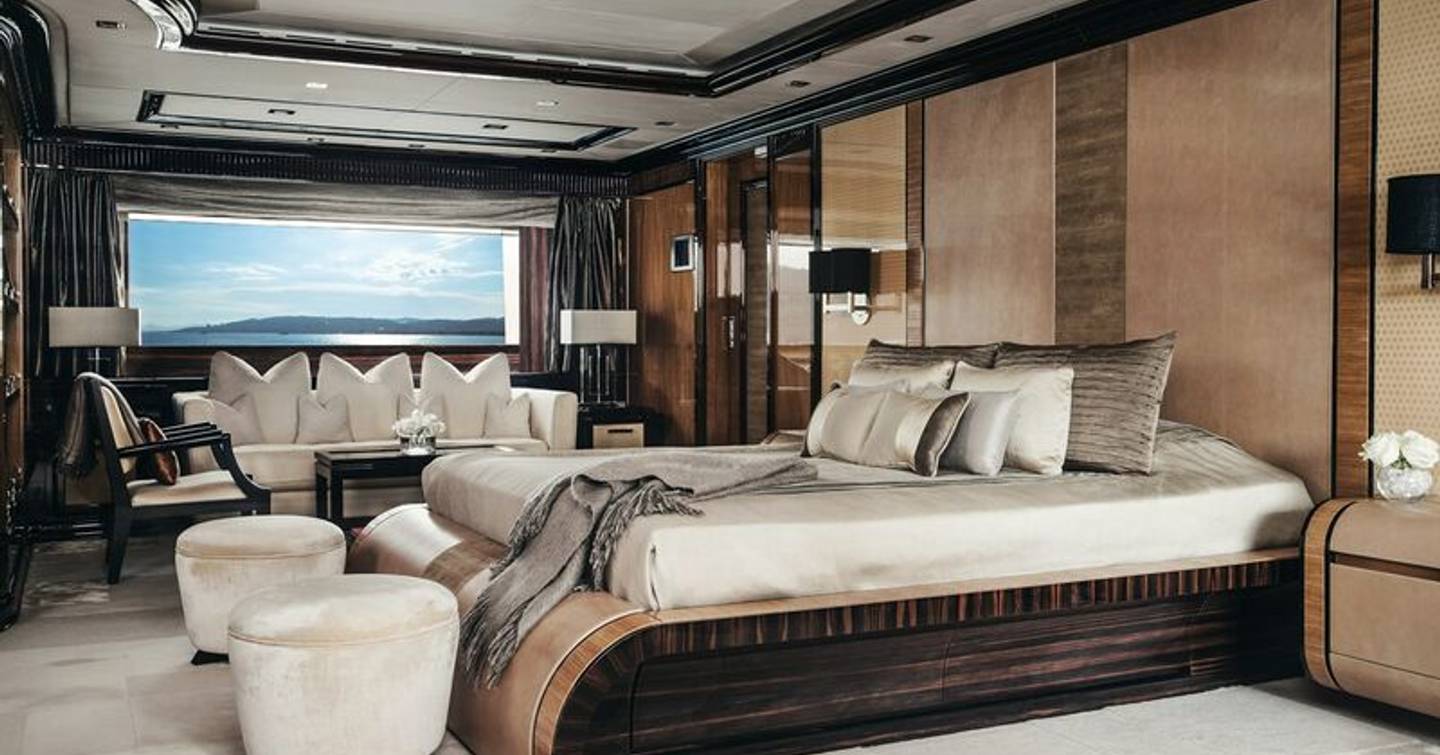 Overview of the master cabin onboard M/Y MEAMINA, central berth facing port with sofa against far wall.