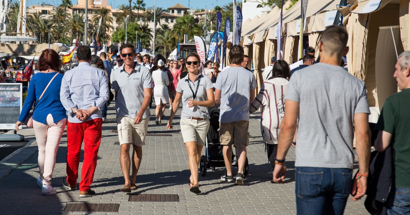 Overview of yacht show visitors and crew walking along dockside at Palma Superyacht Show.