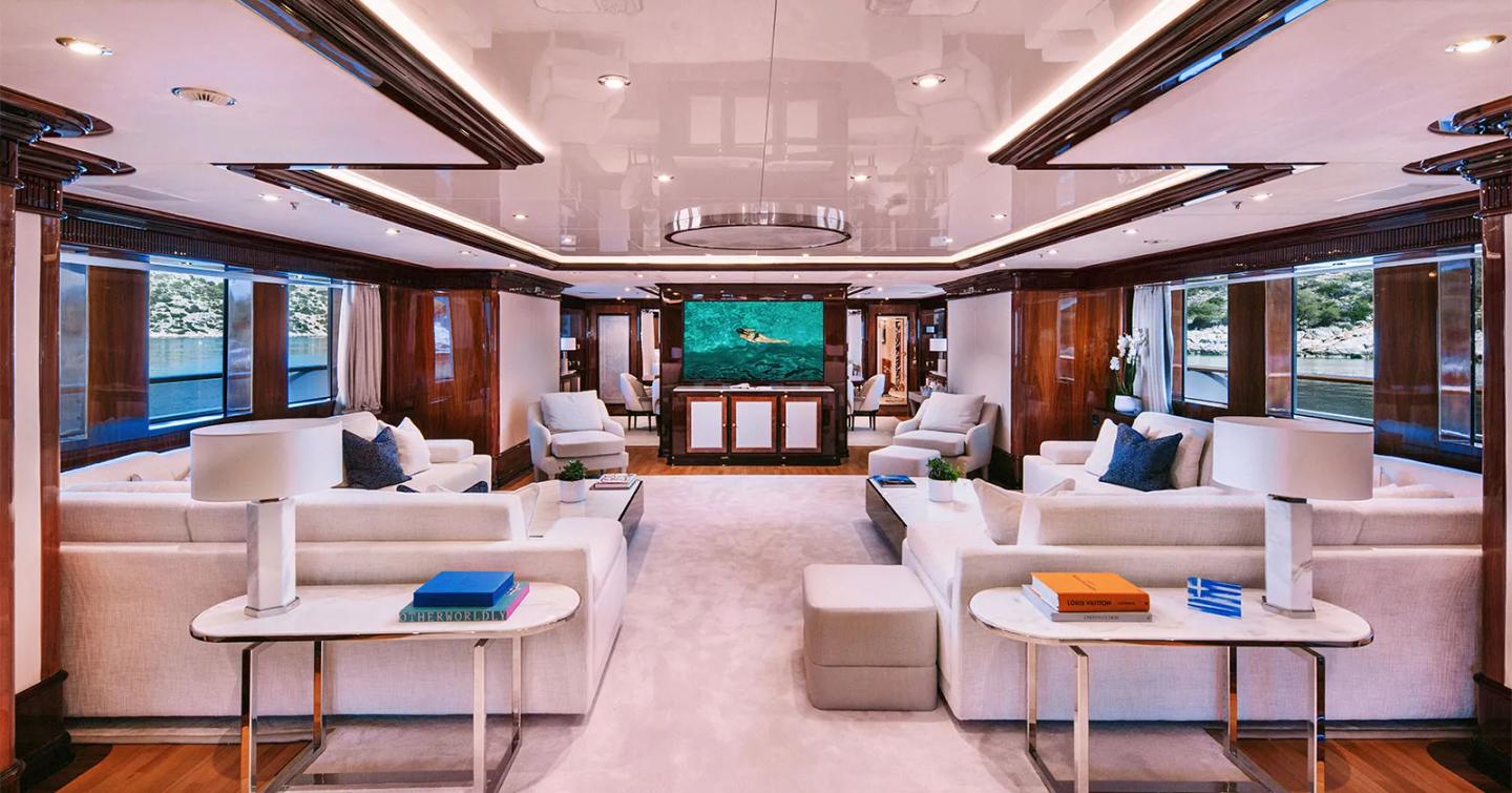 Superyacht Dilara's main saloon with dual white sofas and mounted central TV
