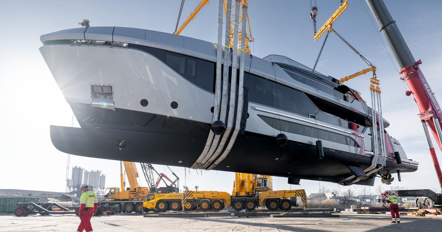 Van der Valk superyacht Shine in air on way to launch with worker underneath