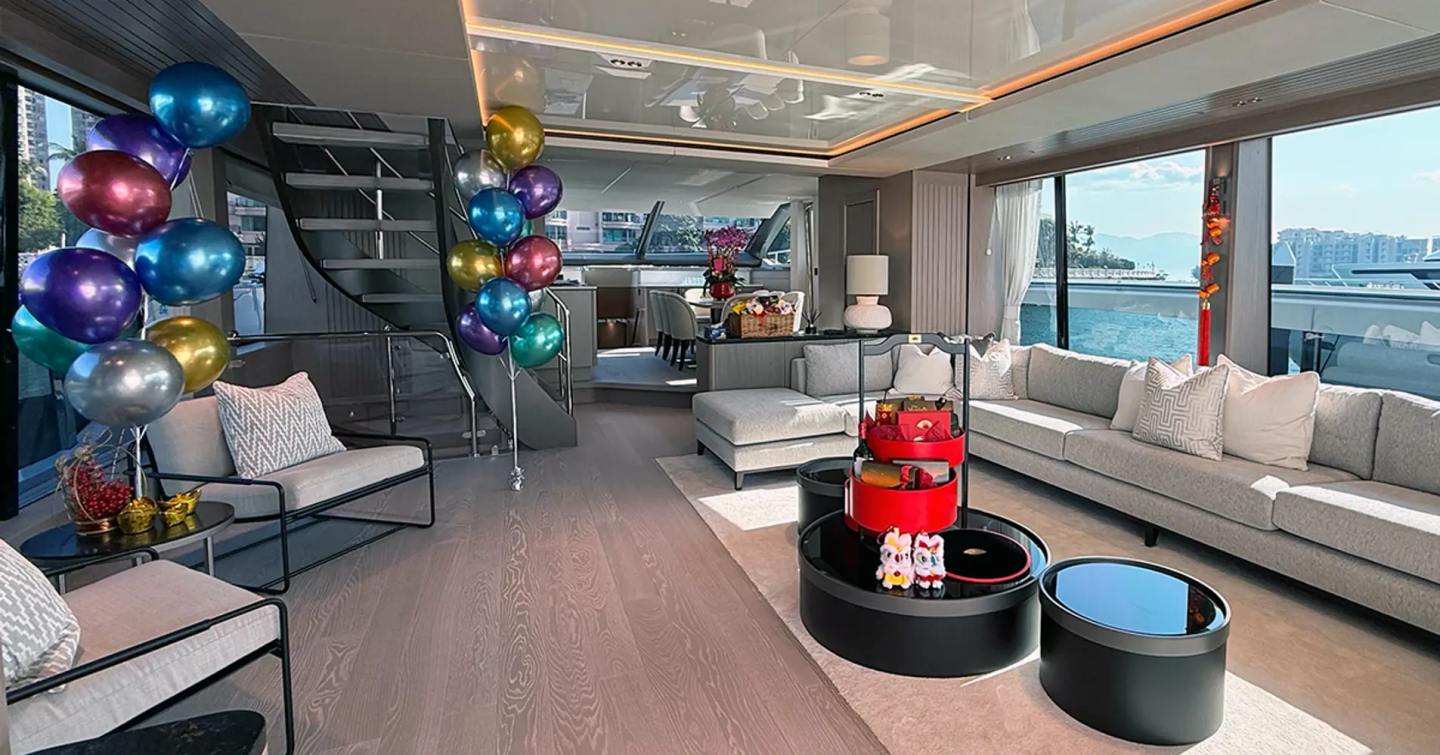 Fourth 27m Sunseeker 90 Ocean Enclosed motor yacht main saloon with L-shaped sofa and with multi-coloured balloons