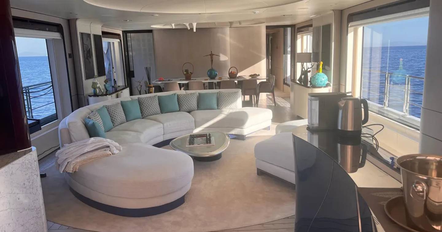 Superyacht Dagusha V main saloon with curved white seating and forward dining area 