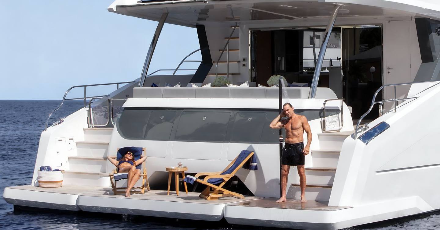 Oceanwalker S60 Catamaran stern with couple sunbathing on deck chairs 