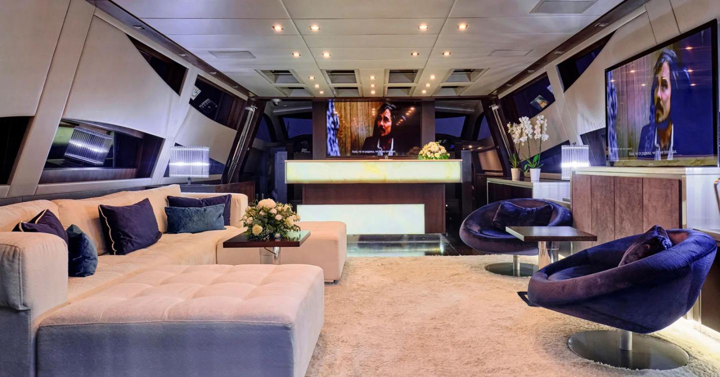 Motor yacht Bagheera main saloon with U-shaped sofa and mounted TV