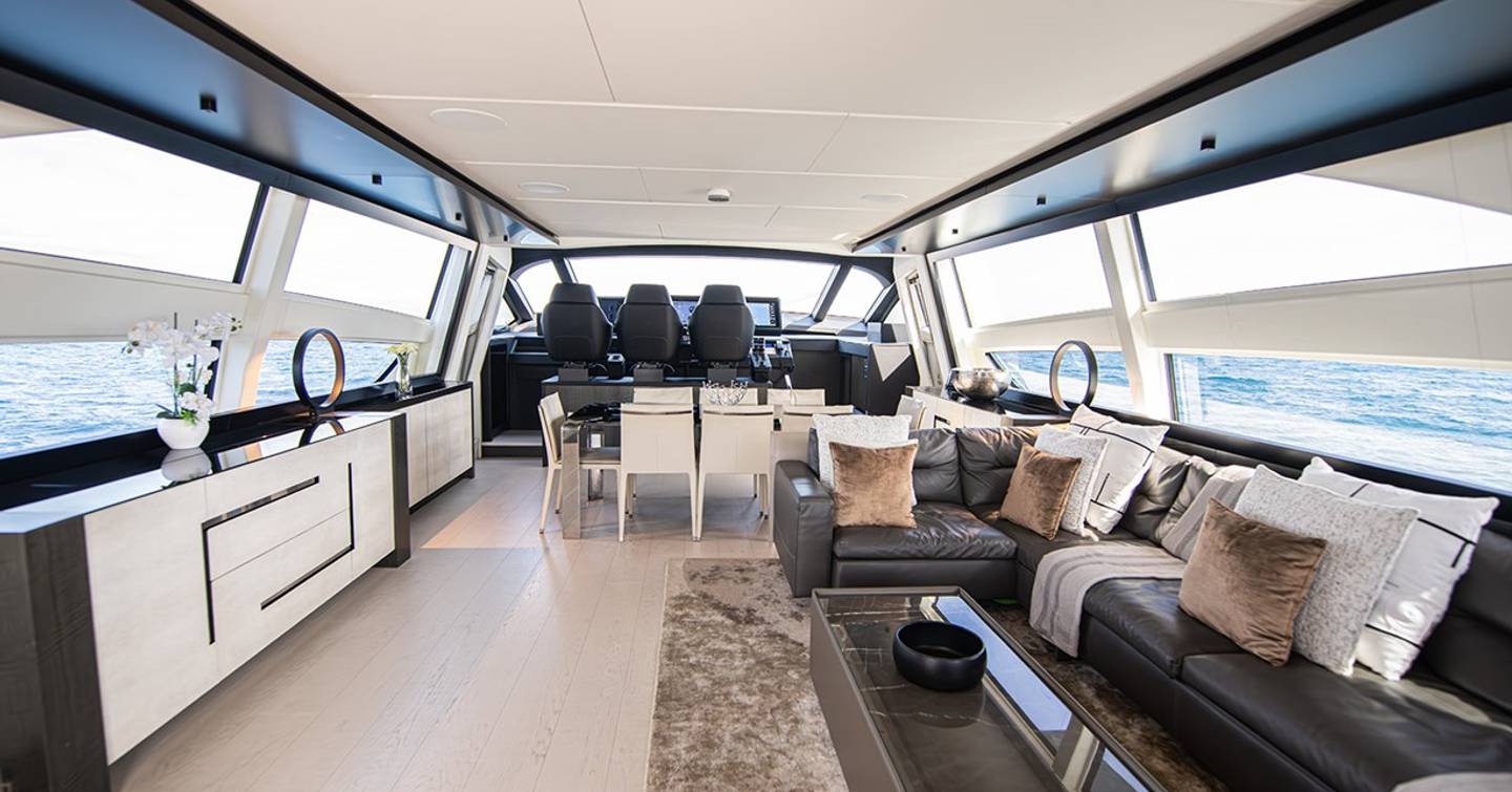 Motor yacht Magic of Ayr main saloon with dining area and black L-shaped sofa