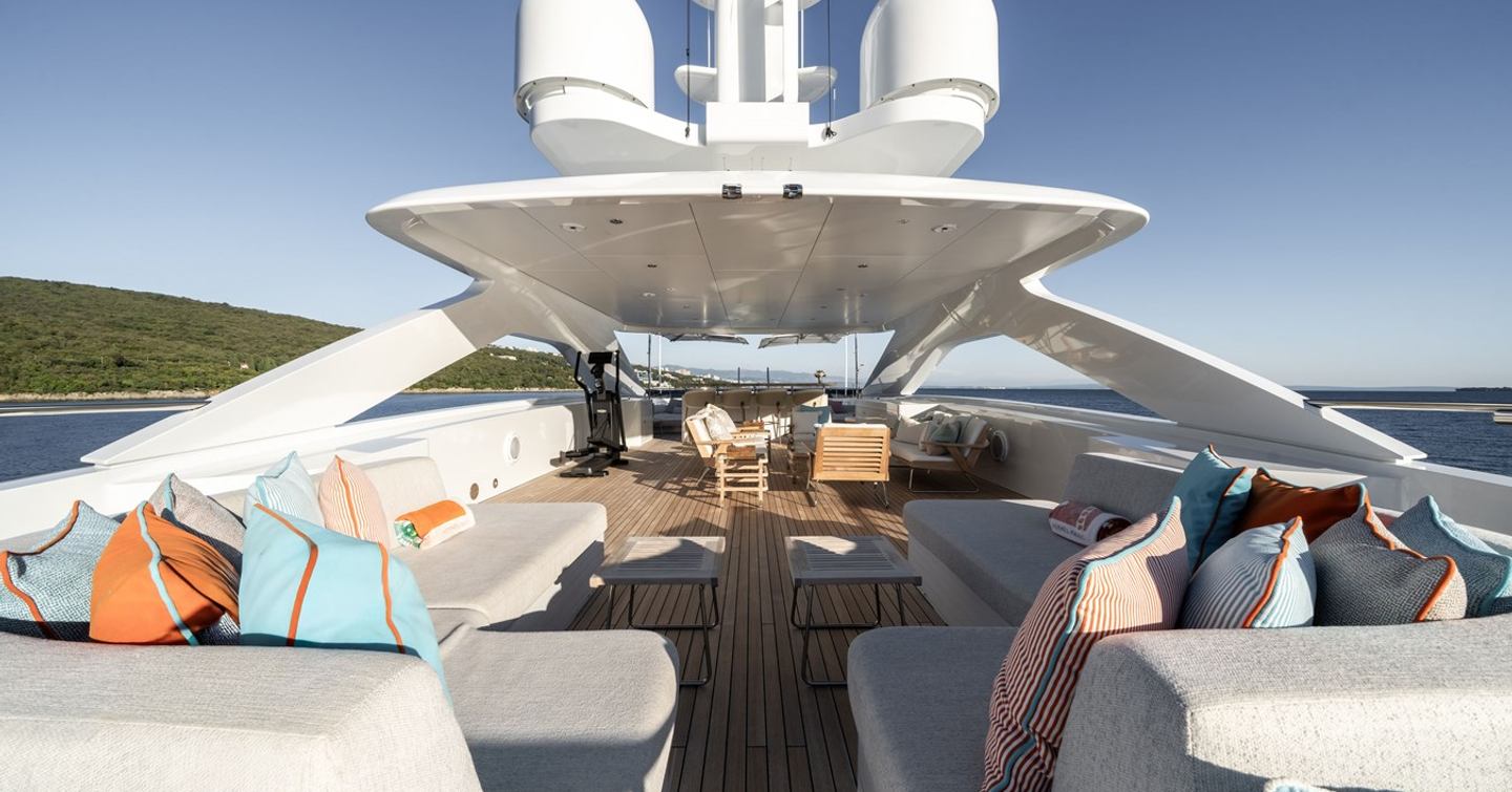 Superyacht Reliance sundeck with L-shaped grey sofas and alfreso dining