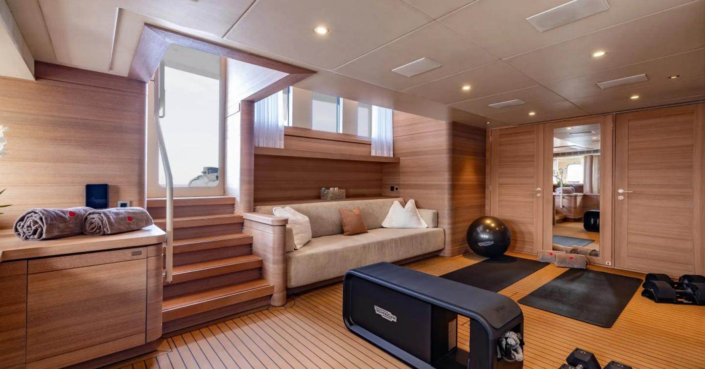 Expedition yacht Bijin interior beach club with beige seating and gym area 