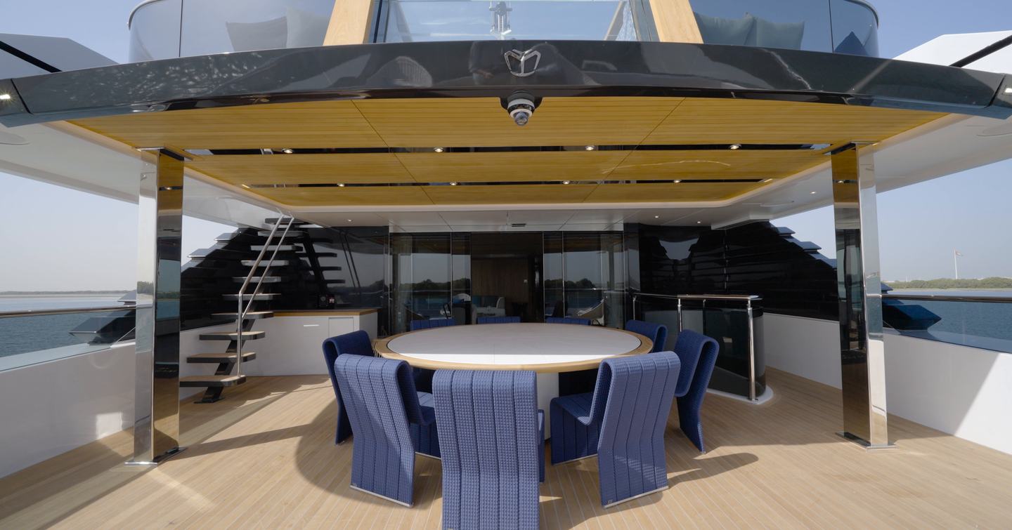 Bridge deck aft dining area aboard the Gulf Craft Majesty 145 with shaded outdoor table and views over the beach club