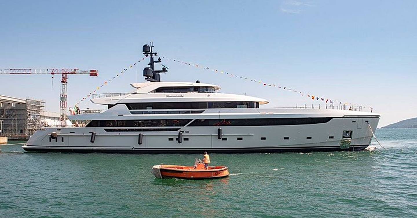 Side view of Sanlorenzo LAMMOUCHE heading out of dock during launch ceremony, adorned with flags and surrounded by sea