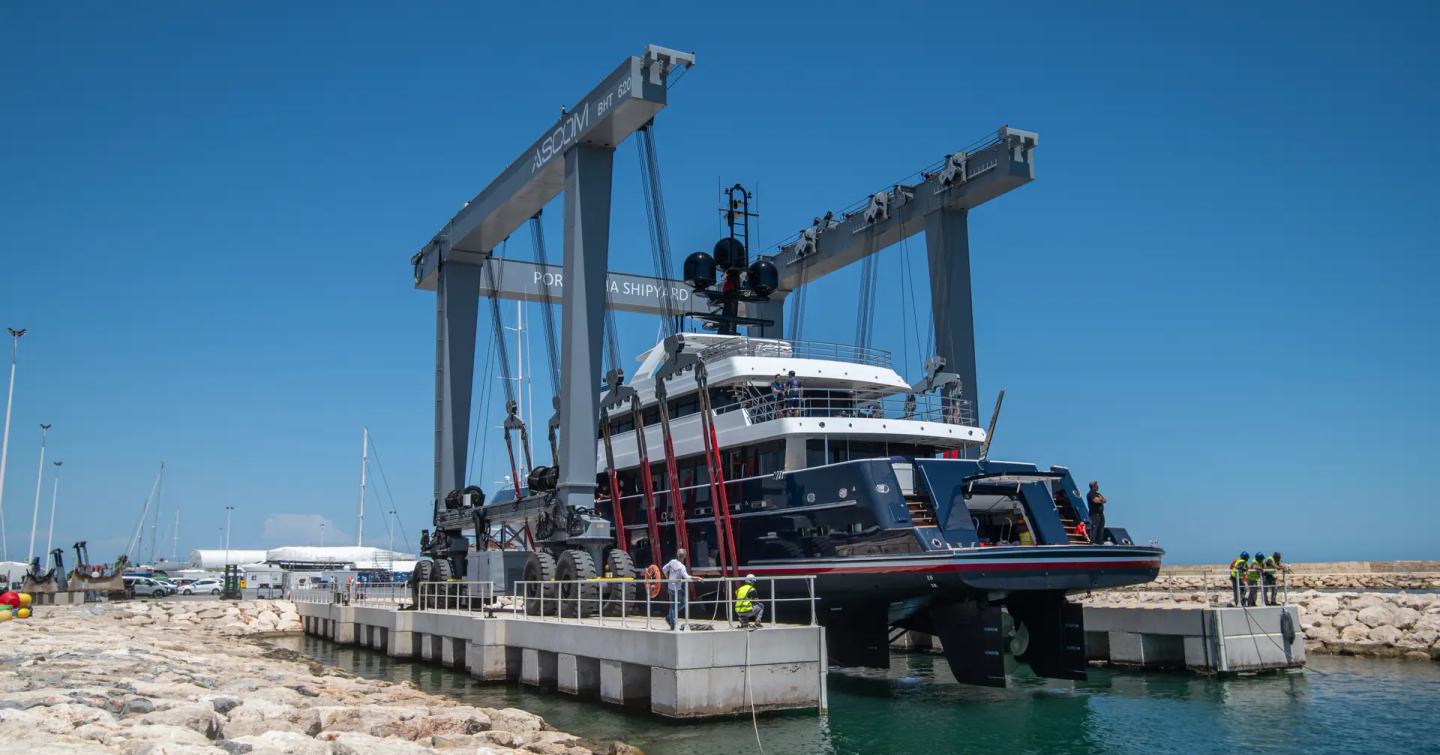 Stern shot of Cheoy Lee Explorer Yacht Avalon 101 being lowered into water at launch post-refit