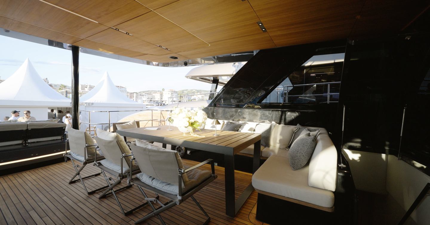 Sunreef Ultima 88 cockpit dining area with L-shaped seating beneath the flybridge overhang