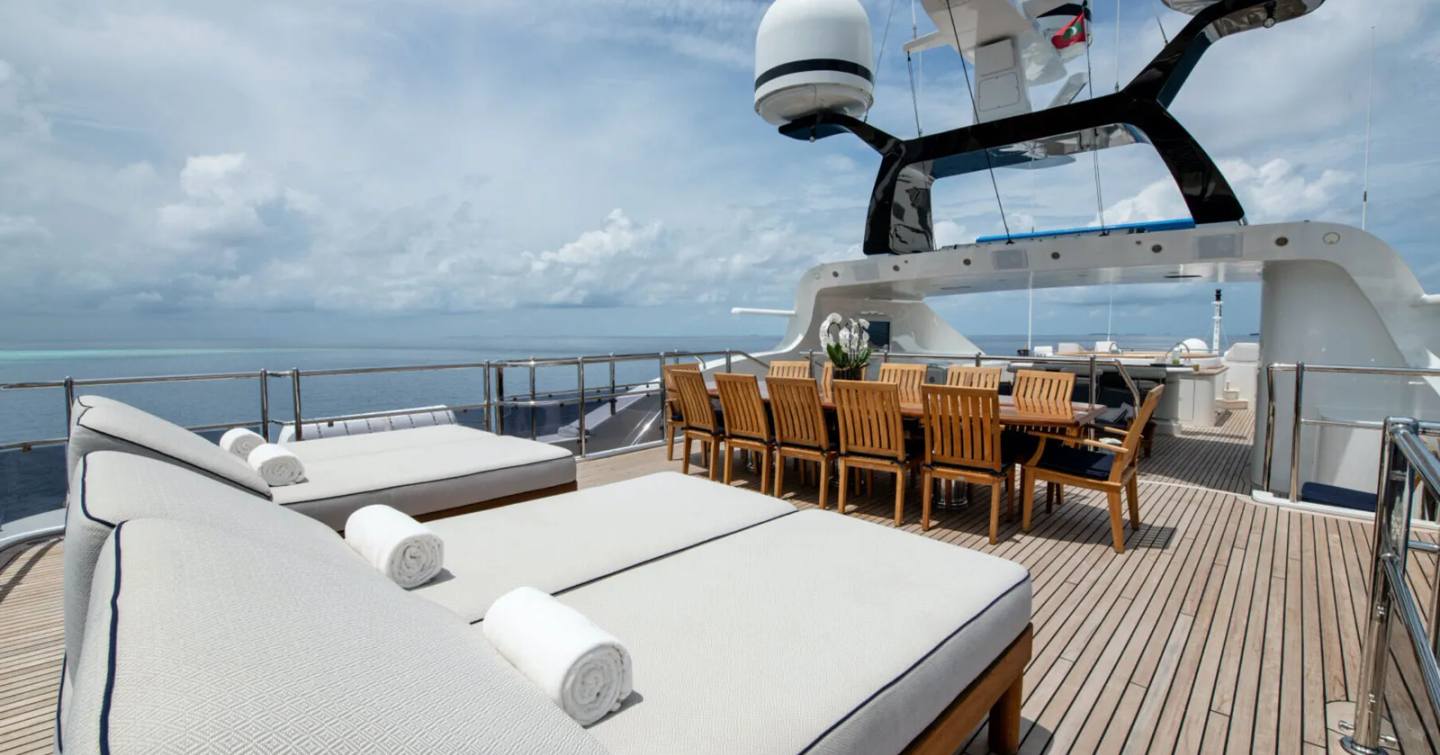 Superyacht Jaguar's upper deck with sunpads and dining table