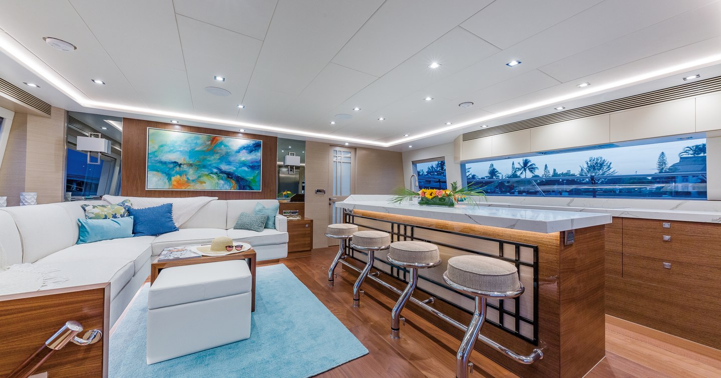 Overview of the main salon onboard the Horizon PC68. L shaped sofa to port with a wet bar and stools to starboard.