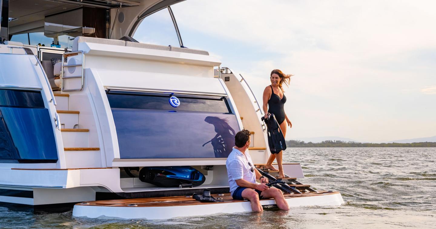 Couple on lowered hydraulic stern platform of Riviera 5600 Sport Yacht Platinum Edition motor yacht