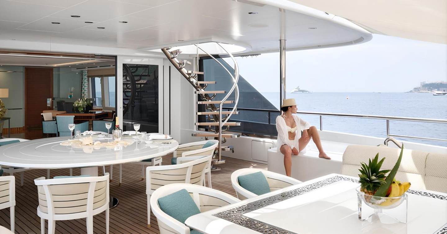 Superyacht Philosophy's main deck aft with circular dining table and staircase