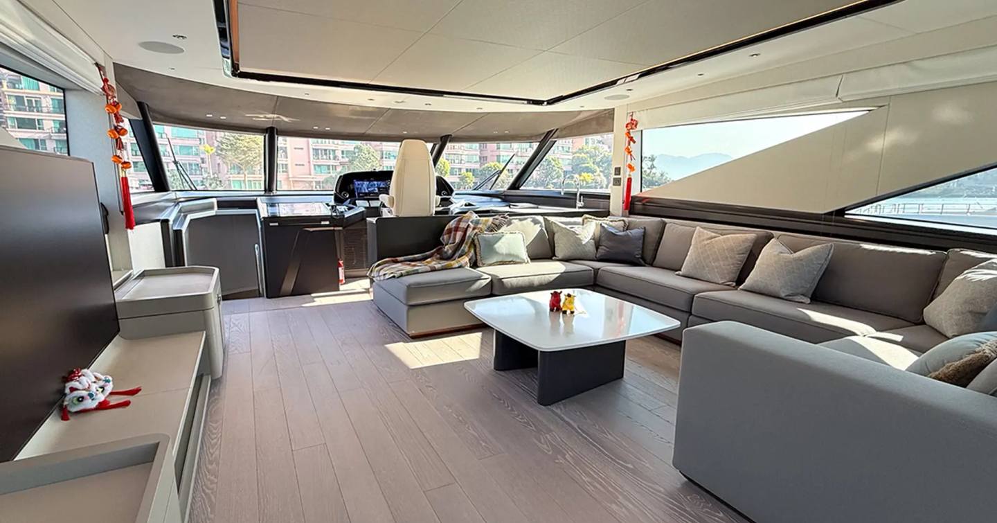 Fourth 27m Sunseeker 90 Ocean Enclosed motor yacht main saloon with grey U-shaped sofa and helm station