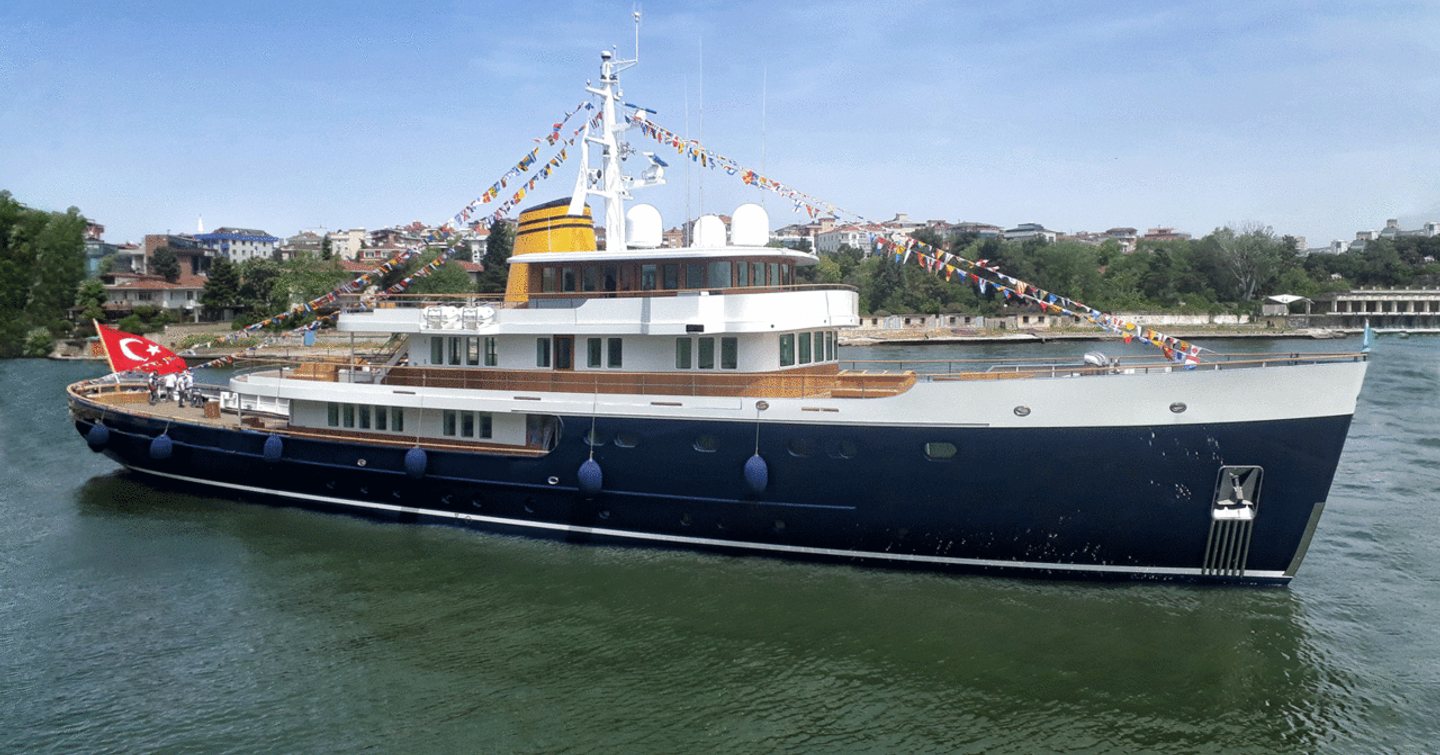 Blue II yacht decorated in bunting anchors in waters to celebrate its launch from Turquoise Yachts