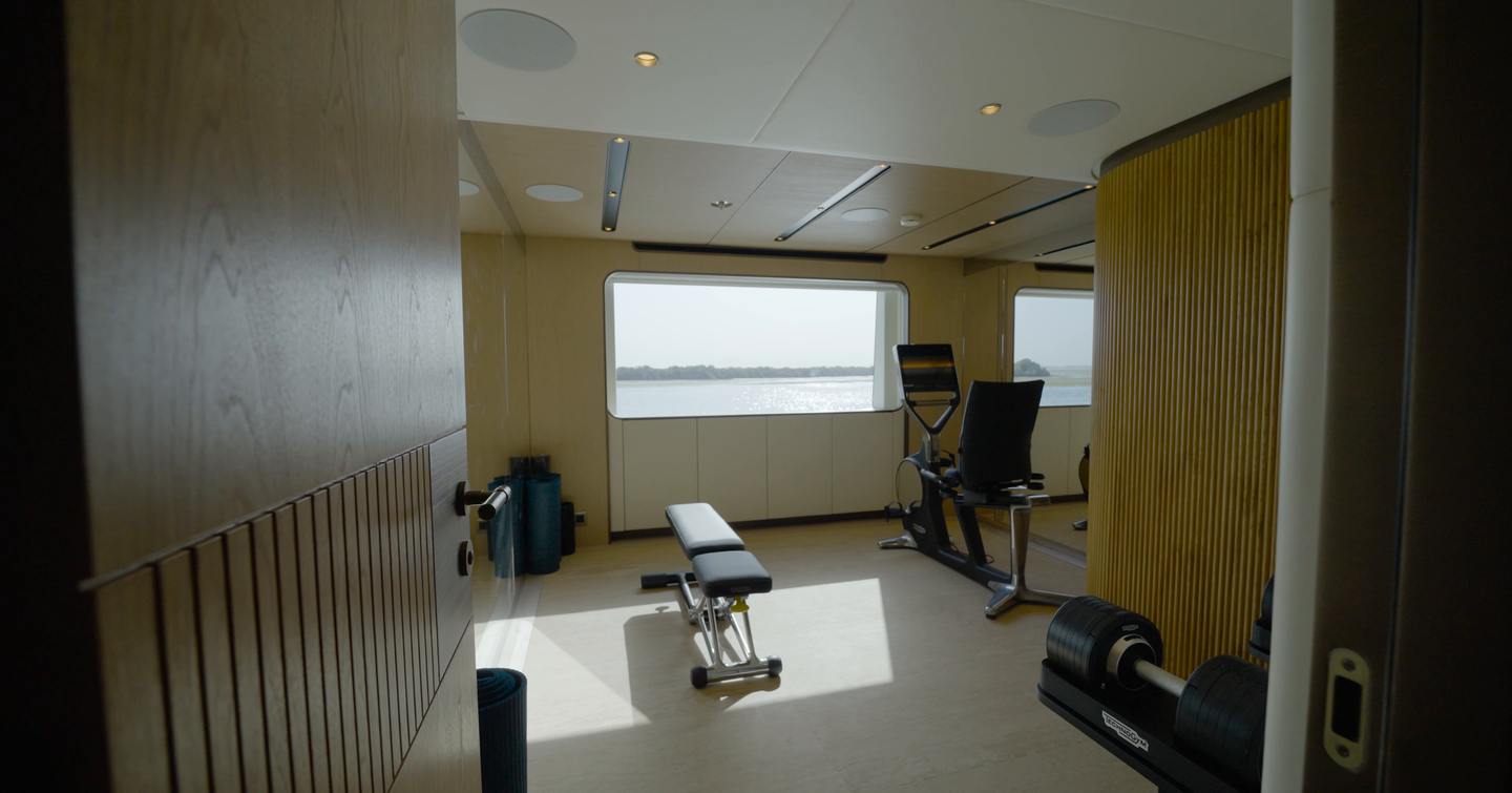 Flexible gym aboard the Gulf Craft Majesty 145 with fitness equipment, windows and configurable guest space