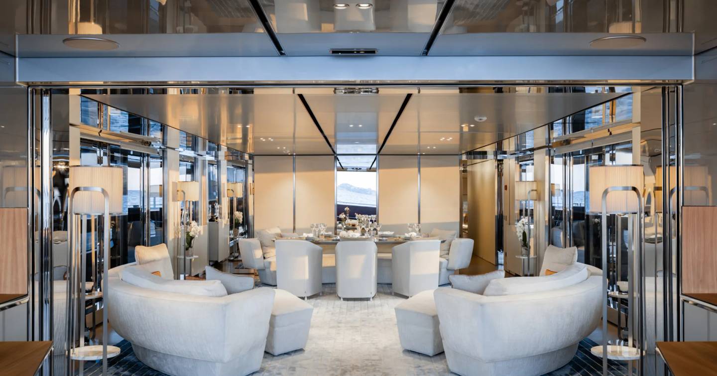 Superyacht Flying Dagger III main saloon with curved white seating and mirror detailing
