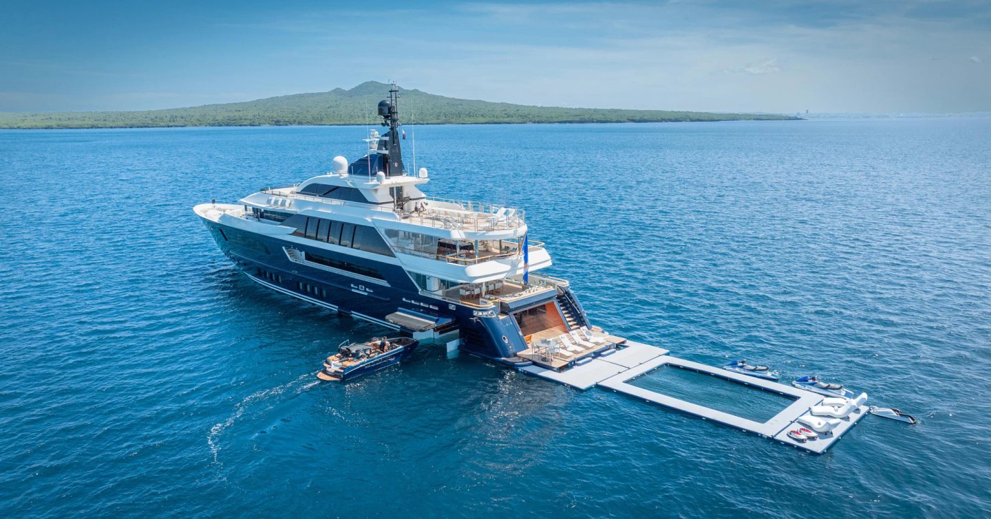 CRN Superyacht Odyssey at anchor with tender entering floodable garage and extended inflatable beach club 