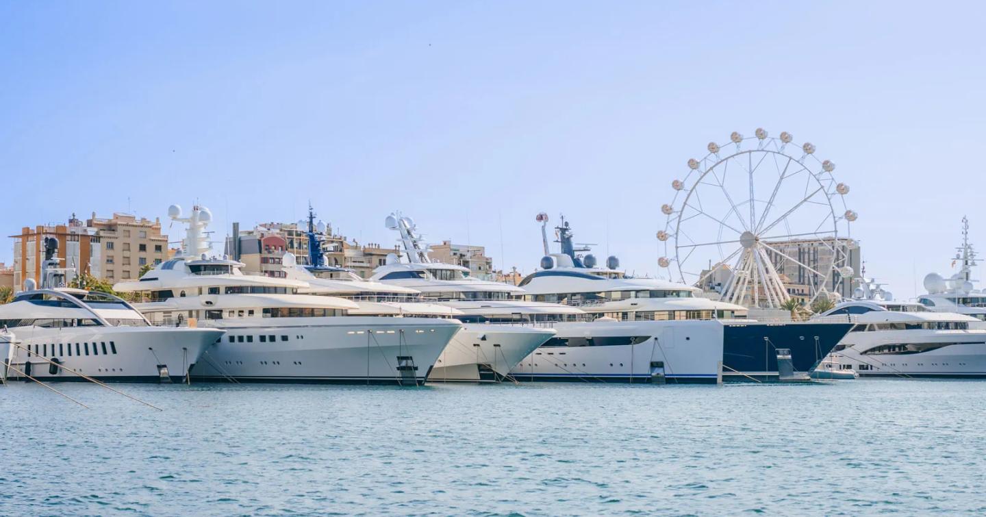 Superyachts docked at Marina Port Vell in Barcelona with ferris wheel in background