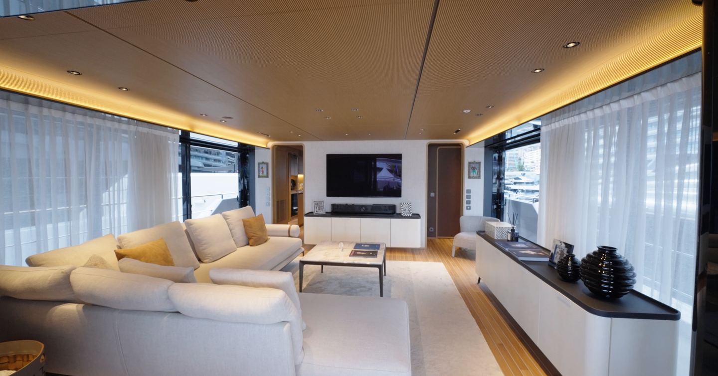 Custom Line Navetta 38 bridge deck saloon with cosy seating area, large windows and TV opposite sofa