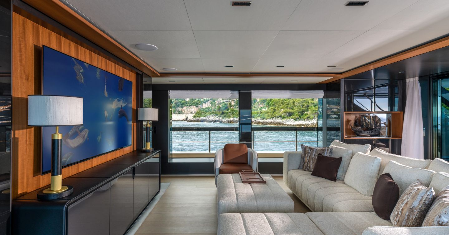 Motor Yacht Sairu upper saloon with L-shaped sofa and mounted TV
