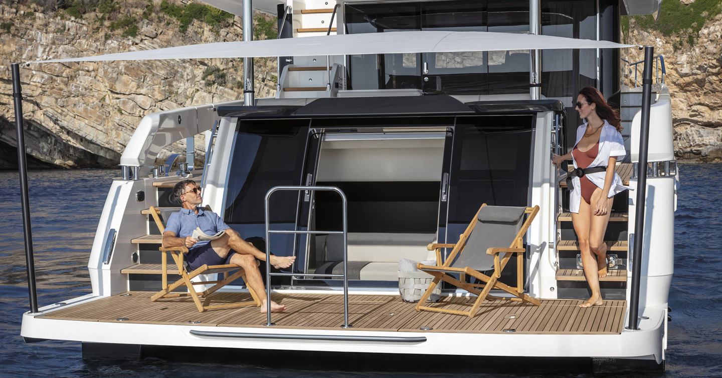 Swim platform/ beachclub environment onboard Absolute Navetta 64, two guests enjoying the sun.