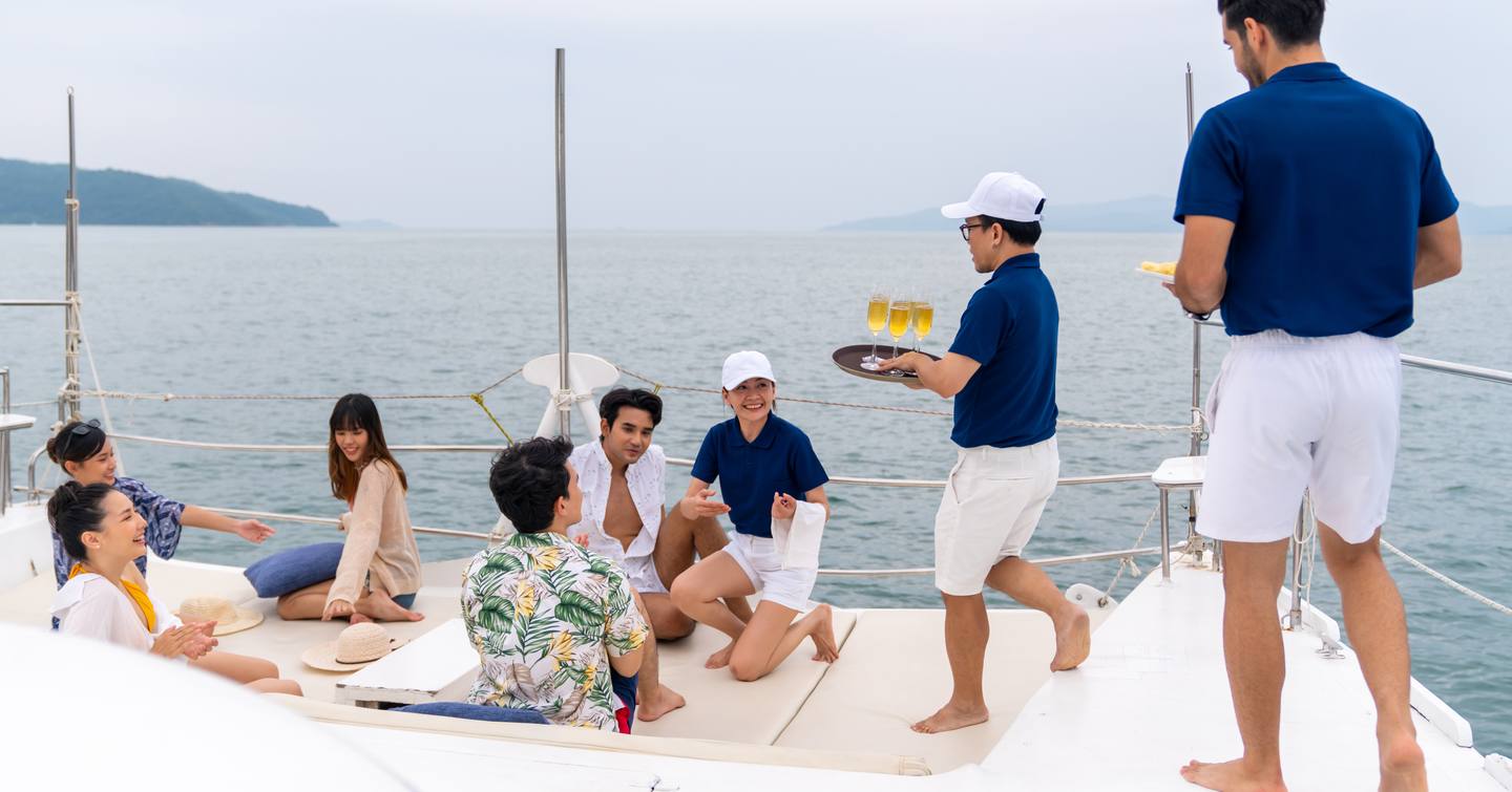 Crew serving drinks to guests on sundeck of superyacht