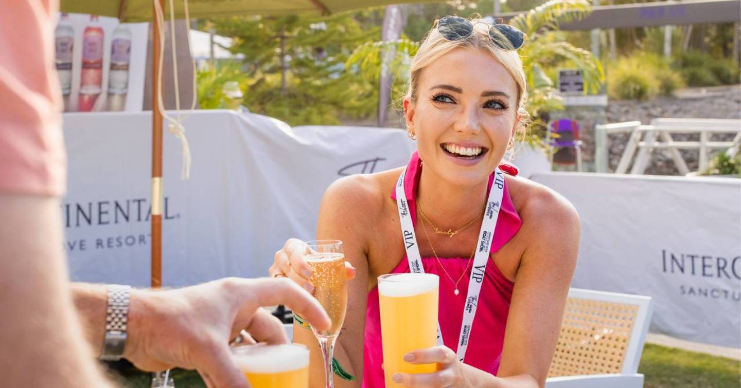 A visitor to the Sanctuary Cove International Boat Show wearing a VIP lanyard enjoying drinks