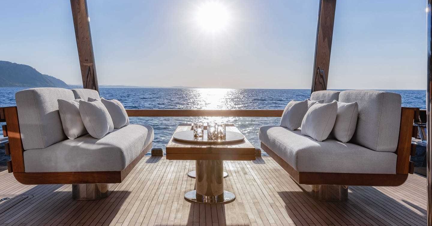 Al fresco seating onboard Magellano 25 Metri, facing sofas with coffee table in centre, overlooking sea