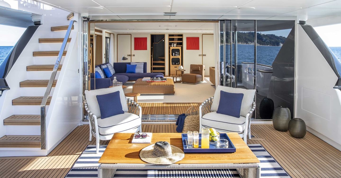 Motor yacht Numero Dix main aft deck shaded seating with blue and white striped rug