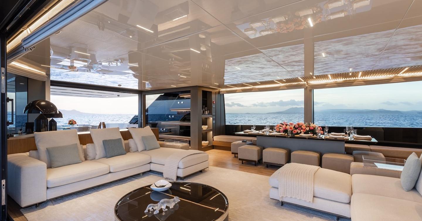 Superyacht Ambar main saloon with dual L-shaped whitesofa and port side dining area 