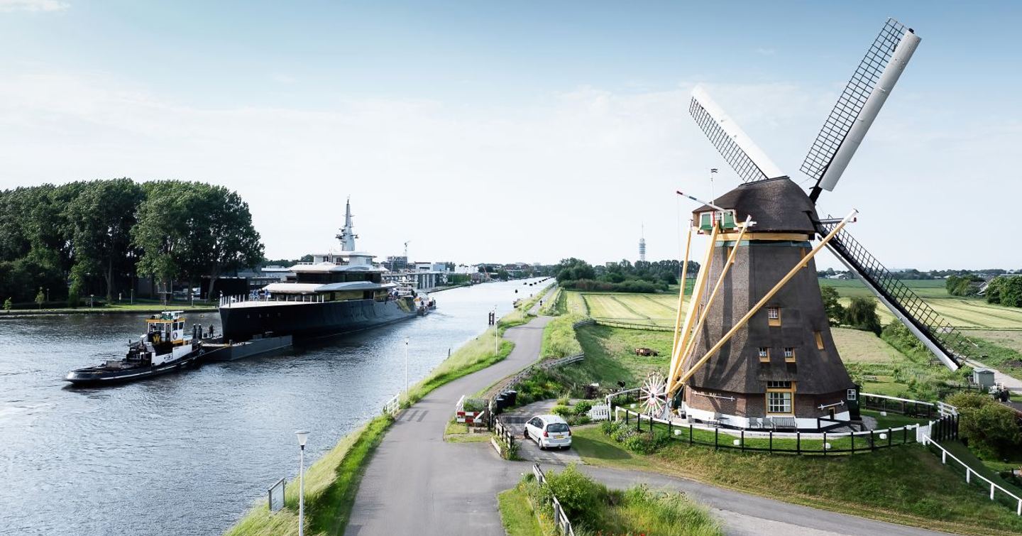 Feadship Superyacht Thalassa (Project 826) following tugboat next to windmill in Dutch river