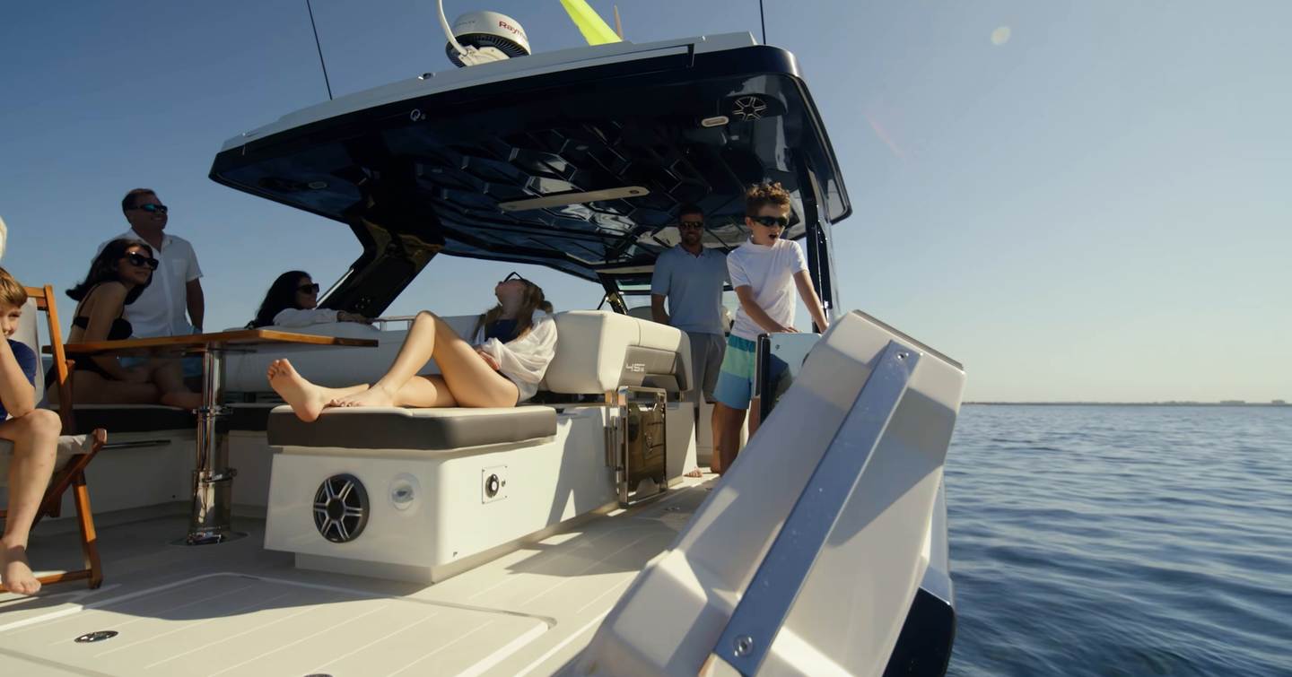 Aquila 45 Sport cockpit with guests relaxing under hardtop and balcony partially open