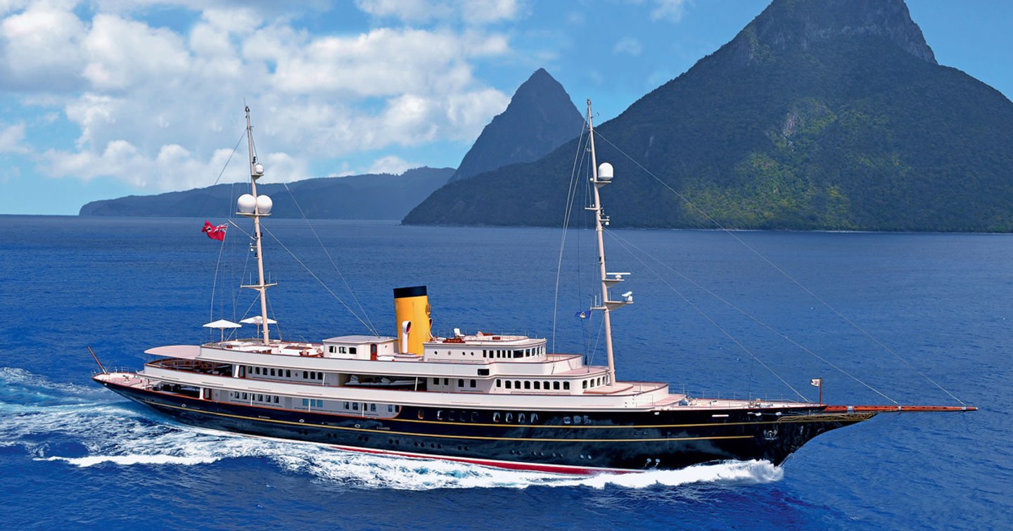 Superyacht NERO underway, surrounded by sea and mountains in background.