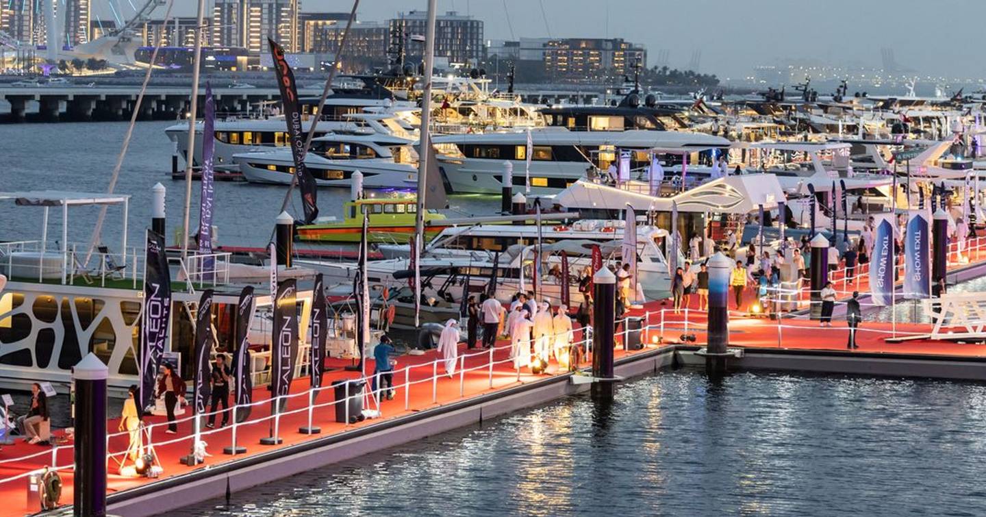 Yachts docked with people walking on walkway at Dubai International Boat Show 