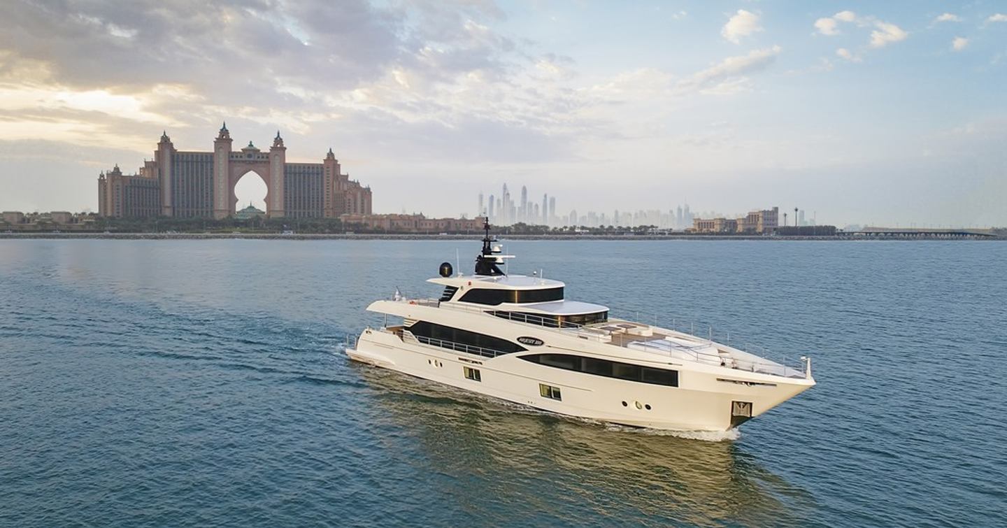 Frontal view of Majesty 100 underway with Dubai Atlantis in background, surrounded by sea