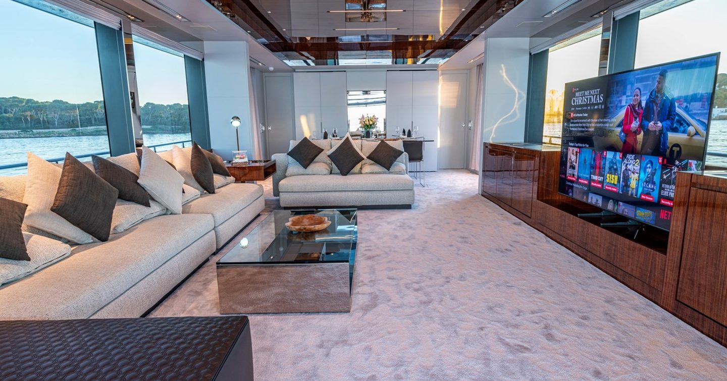 Superyacht Taku main salon with L-shaped seating and mounted tv