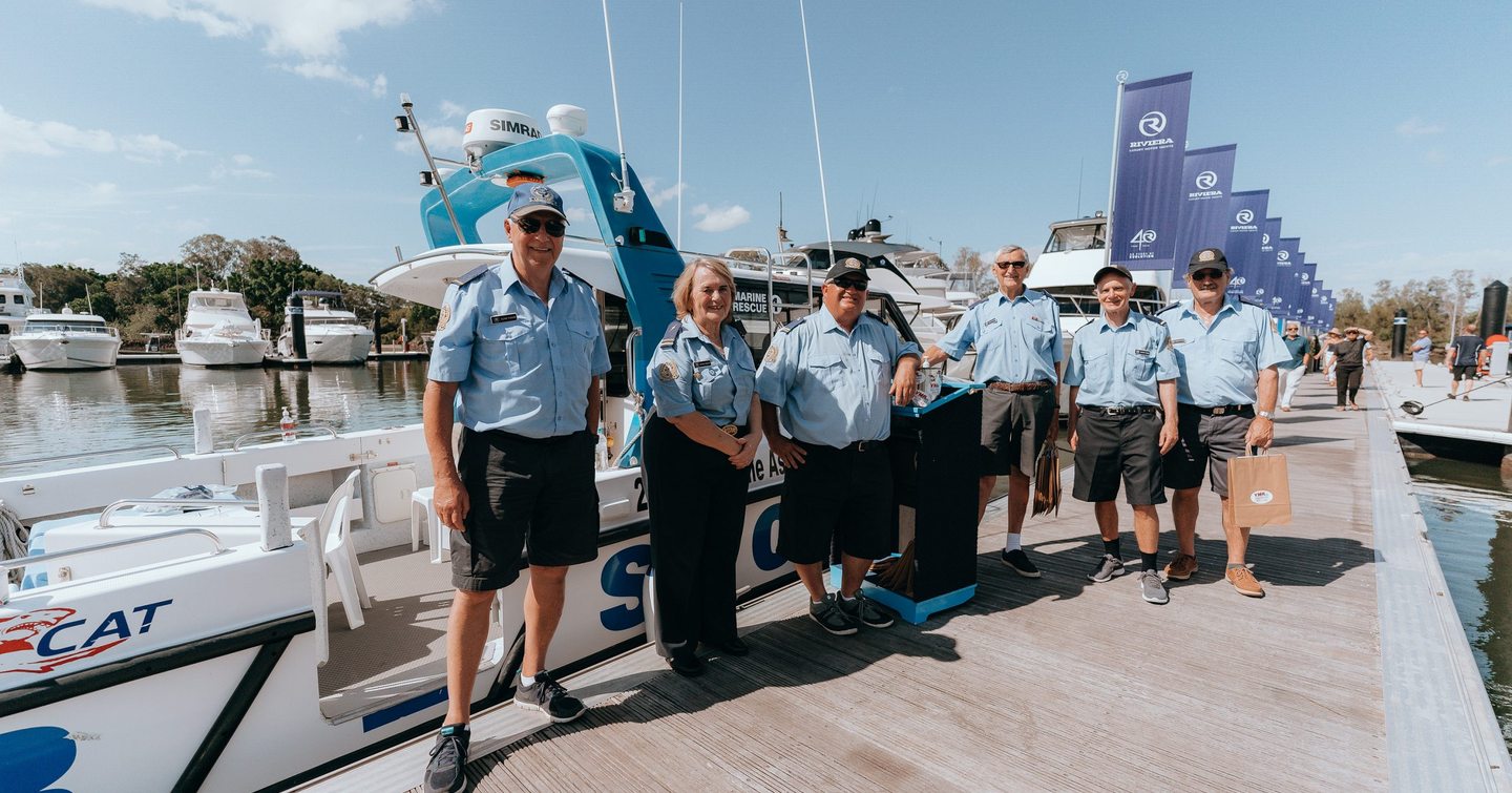 Crew lined up along dock in front of berthed yachts at Sanctuary Cove Boat Show.