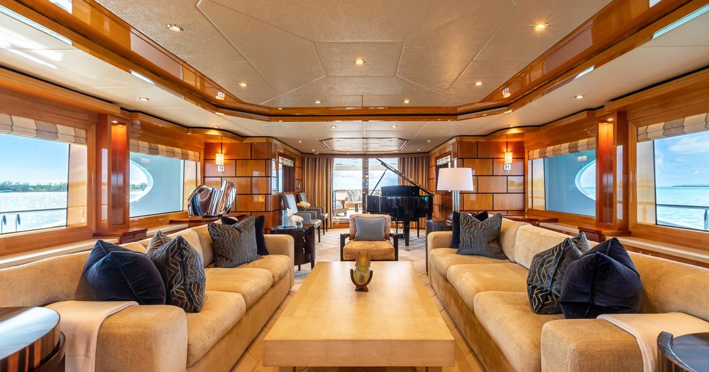 Superyacht Impromptu main saloon with beige furniture and grand piano and wooden furniture