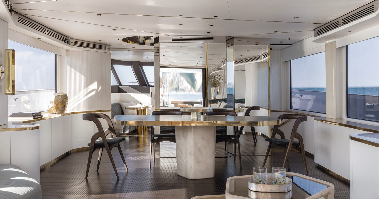 Interior dining area onboard Magellano 25 Metri, large table surrounded by chairs and wide windows overlooking the sea