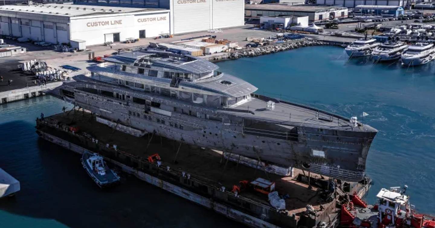 Side view of CRN 143 Project Maranello in transit to the Ferretti Group Superyacht Yard, with Custom Line signs in the background.