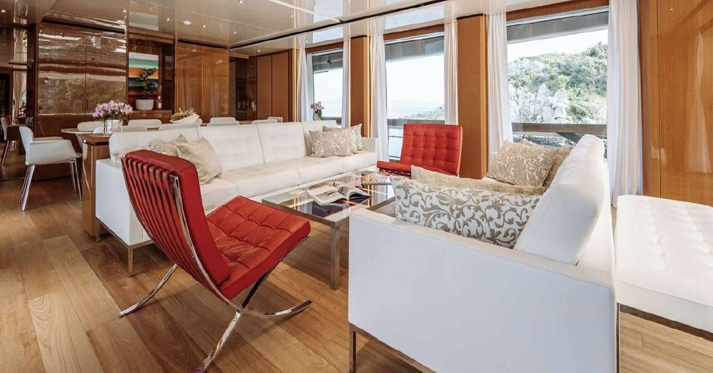 Superyacht Erolia main saloon with white sofas and red plush chairs